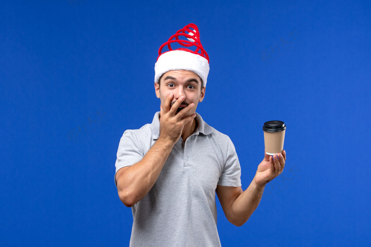 男孩正面图年轻男子拿着咖啡杯在蓝色办公桌上过年男子假期成人杯子圣诞节