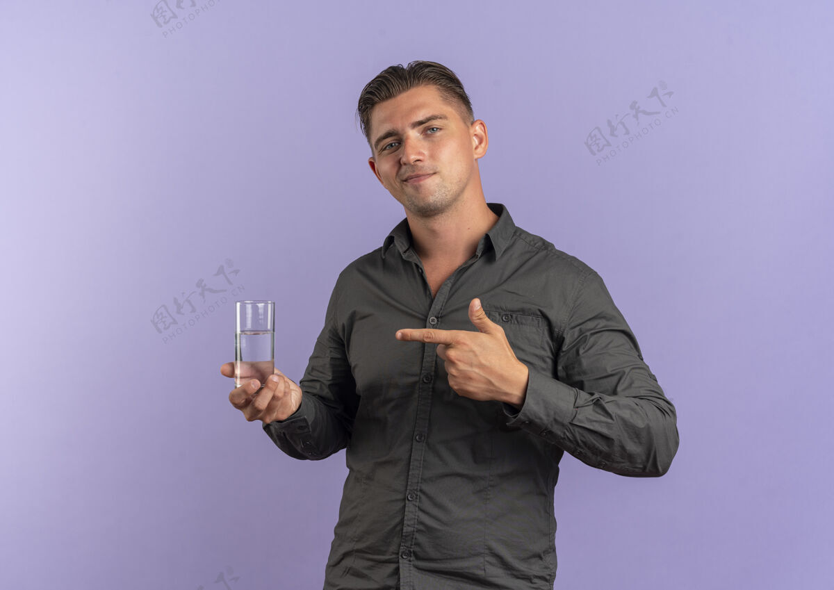 请等一下年轻高兴的金发帅哥拿着 指着紫罗兰空间和复制空间上孤立的一杯水紫罗兰玻璃水