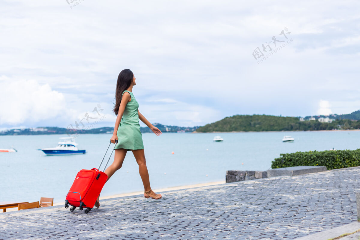 淑女快乐的白种人漂亮的长发优雅的旅游女人在酒店外面穿着红色的手提箱积极时尚旅游
