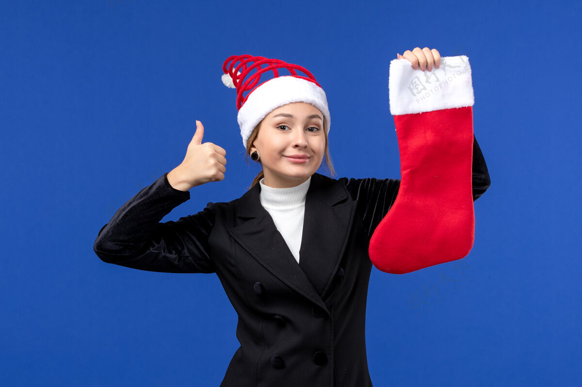 圣诞节正面图年轻女子手持红色圣诞袜在蓝色墙壁上过年过年商人西装爱国