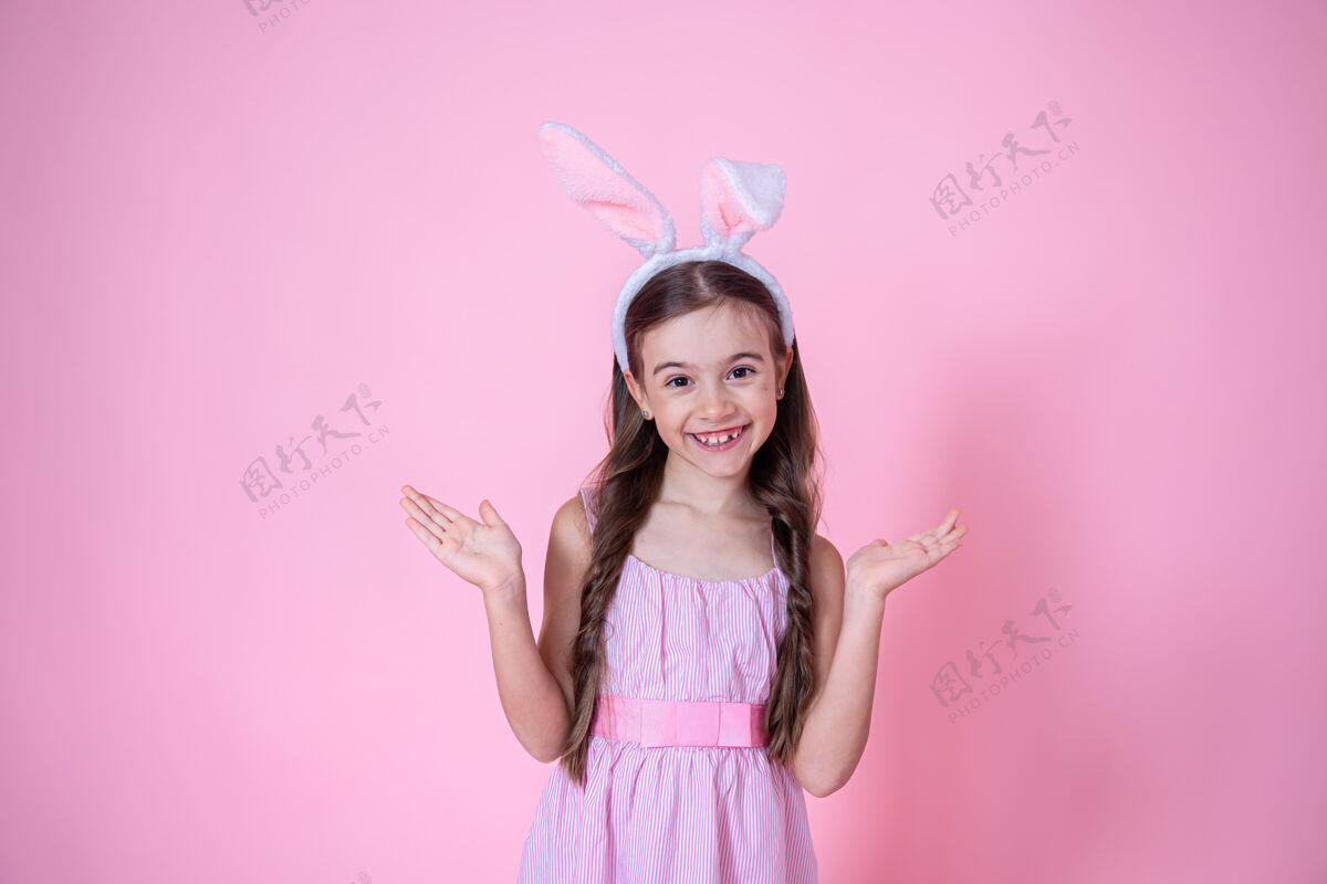 耳朵复活节兔子耳朵的小女孩在粉红色的椅子上摆姿势姿势节日模型