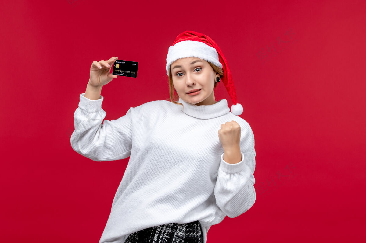 卡片正面图红色背景上手持银行卡的年轻女性圣诞节年轻女性正面