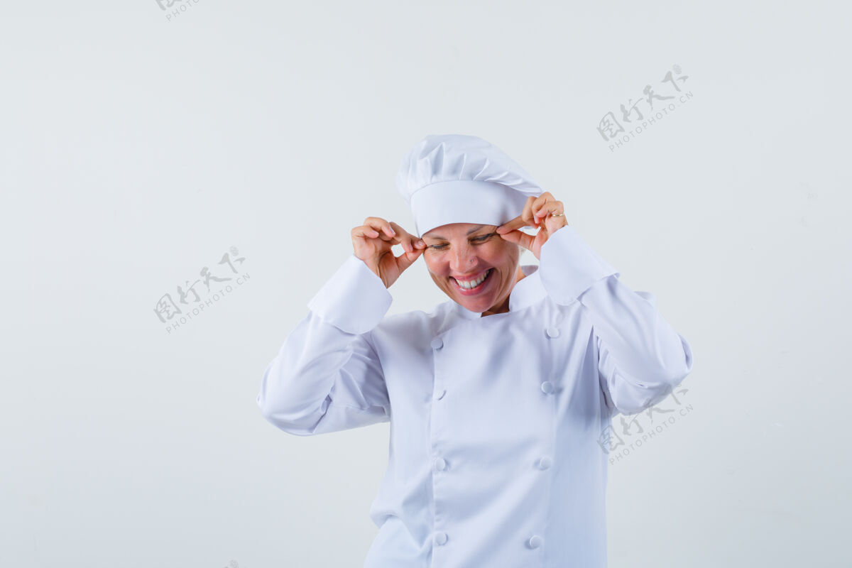 时尚一个穿着白色制服的女厨师捏着她的眼皮 看起来很疯狂厨师乐趣女性