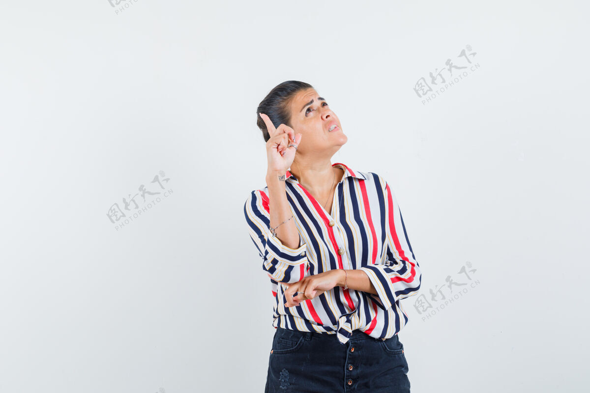 尤里卡穿着条纹衬衫的年轻女子站在思考的姿势 举着手指做着尤里卡手势 看上去沉思不已衬衫可爱沉思