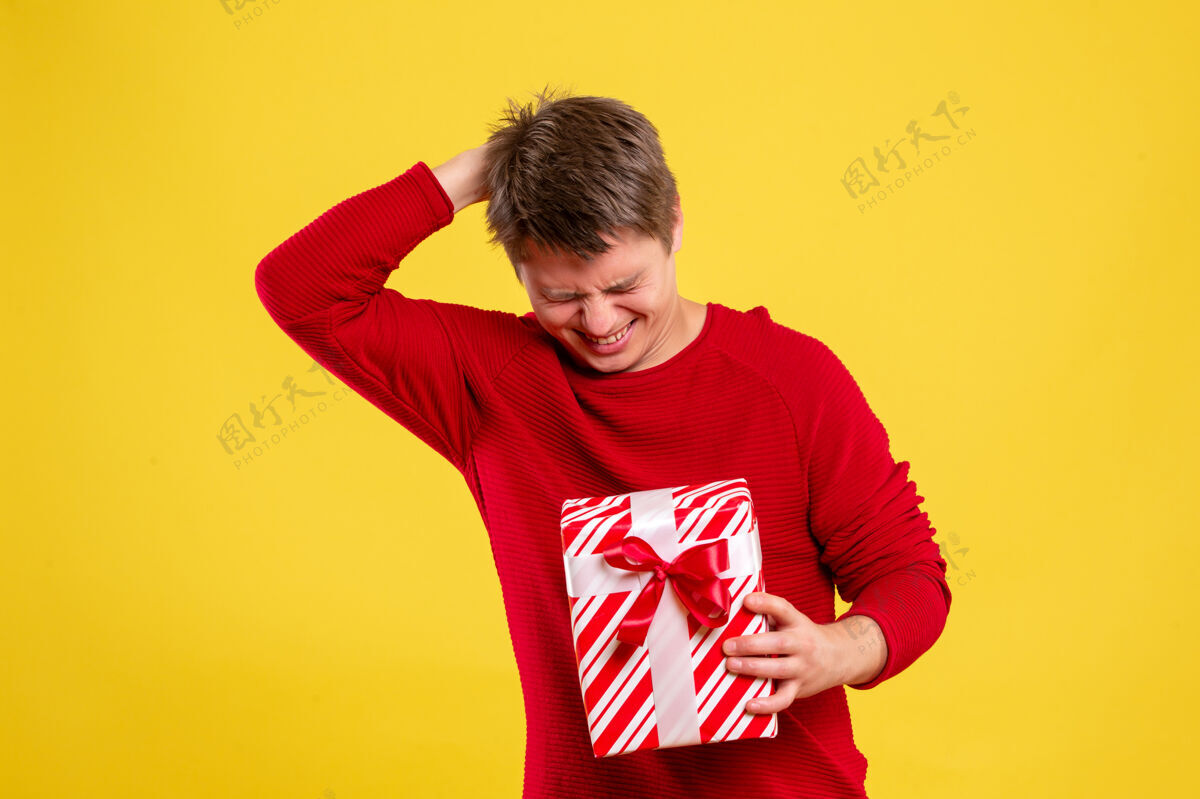 黄色前视图黄色背景上有圣诞礼物的年轻男性情感礼物成人