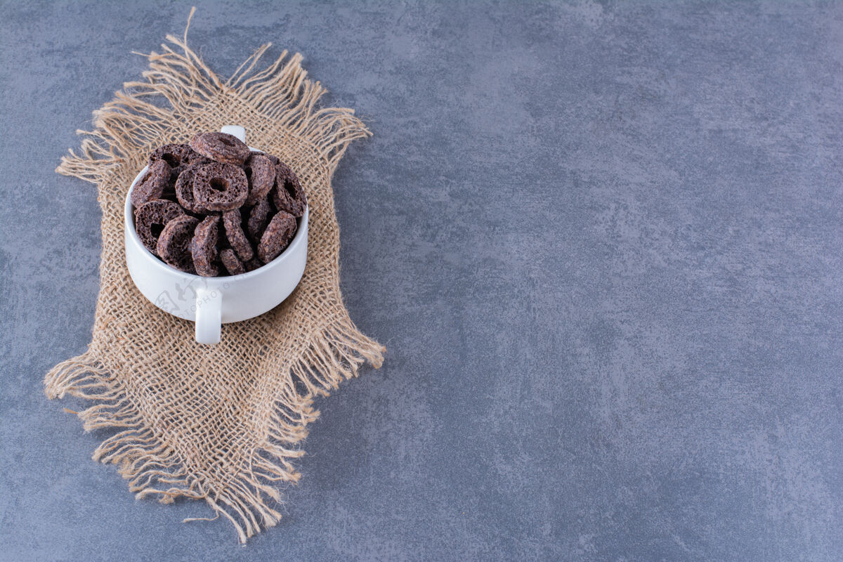 维生素健康早餐 巧克力玉米圈放在石头上的白色碗里能量麦片烹饪