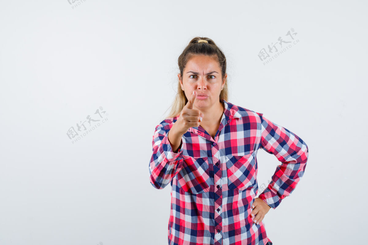 检查年轻女士的肖像警告与手指在格子衬衫 并期待紧张的前视图年轻视图紧张
