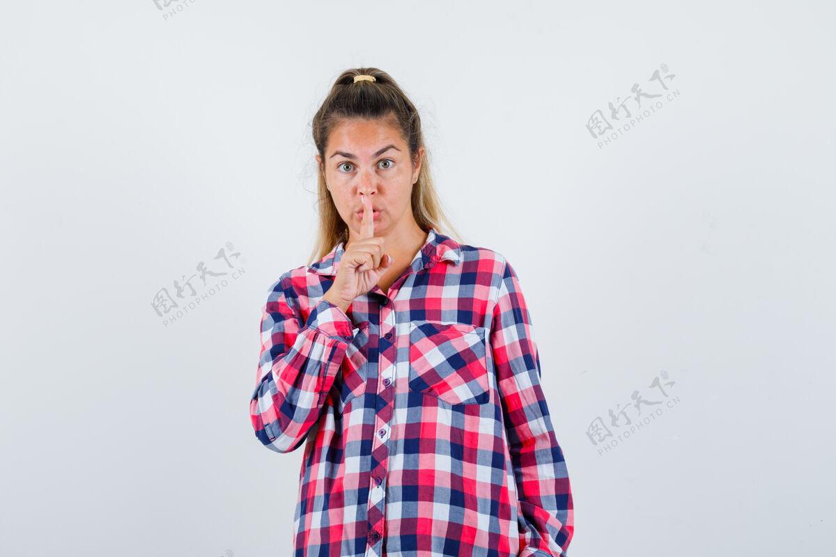 女性穿着格子衬衫的年轻女士表现出沉默的姿态 看上去很小心前视图肖像微笑显示