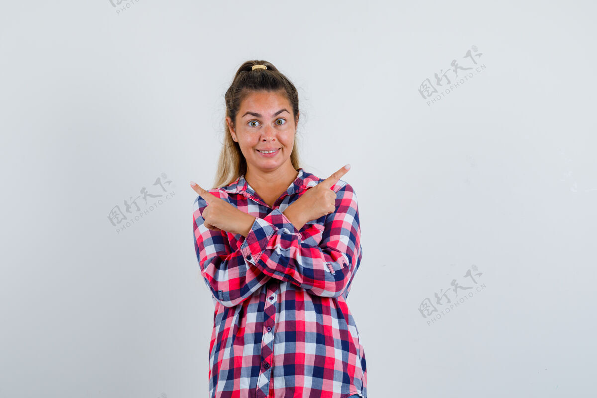 成人照片中的年轻女士穿着格子衬衫指着两边 看上去很开心脸女孩视图