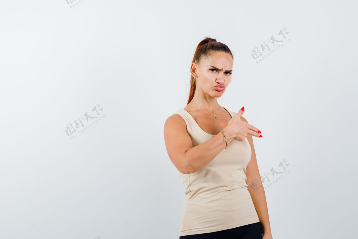 女性身着米色背心的年轻女性 展现出持枪的姿态 看上去很自信 前视图前面时尚手势