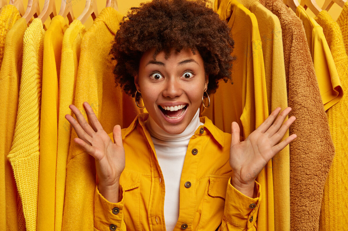 Person快乐的女人站在时尚的购物中心里 快乐的女人站在黄色的购物架上休闲Hanger时尚
