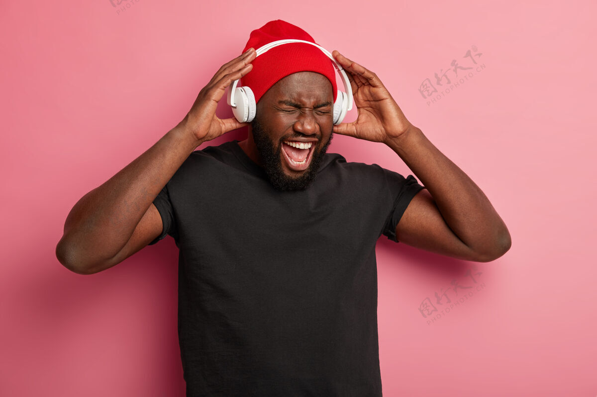 媒体非裔美国人喜欢音乐播放器或录音机 手戴耳机 一边听流行歌曲一边玩得很开心 被隔离在粉红色的墙上聆听积极旋律