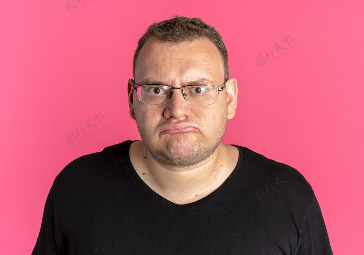 眼镜一个戴眼镜 身穿黑色t恤的超重男子看着镜头 对粉色很不满意站着粉色看起来