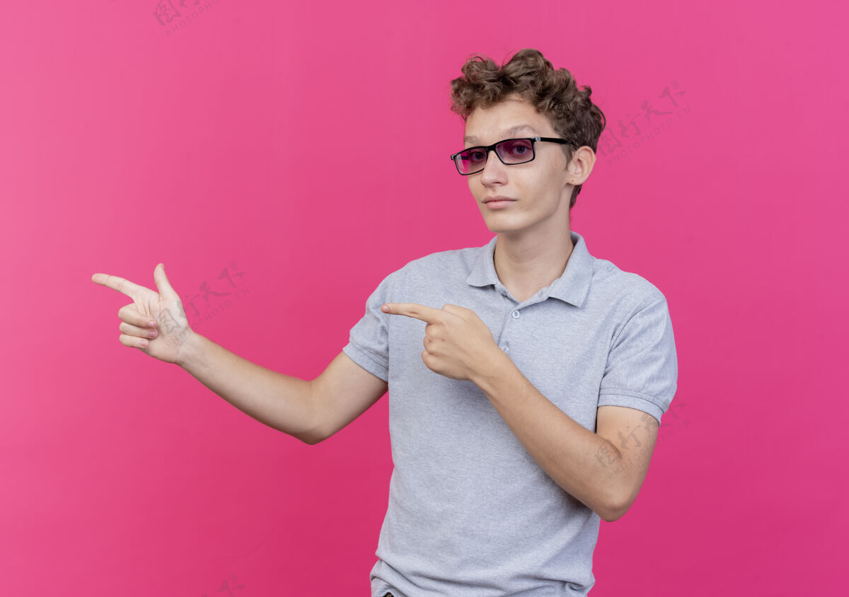 灰色一个戴着黑眼镜的年轻人 穿着灰色马球衫 严肃的脸上用手指着粉色的一边黑色壁板眼镜