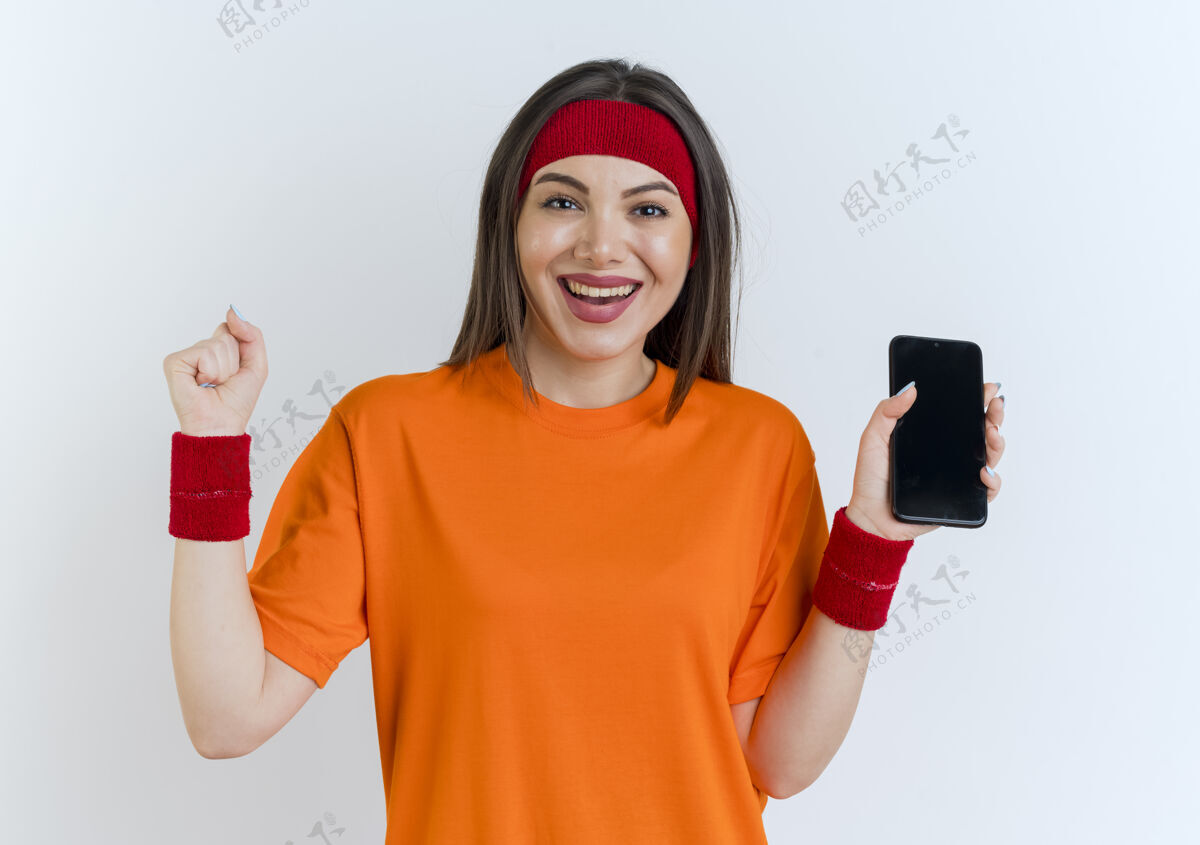 头带快乐的年轻运动女性戴着头带和腕带拿着手机看着做是的手势手机穿女士