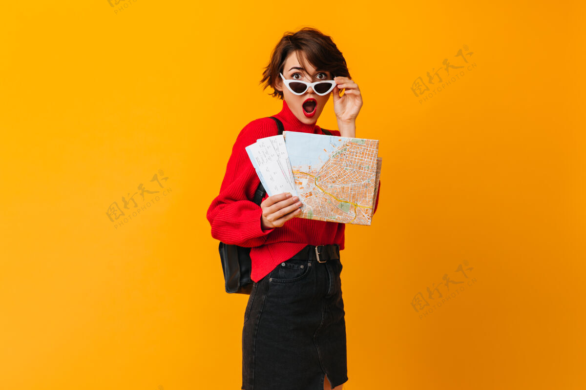复制空间戴着摸地图太阳镜的惊讶女人假期黑发红色毛衣