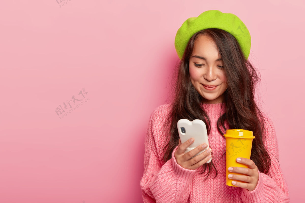 毛衣迷人的黑发年轻日本女子手持现代手机 在网上聊天发短信超大通讯游戏