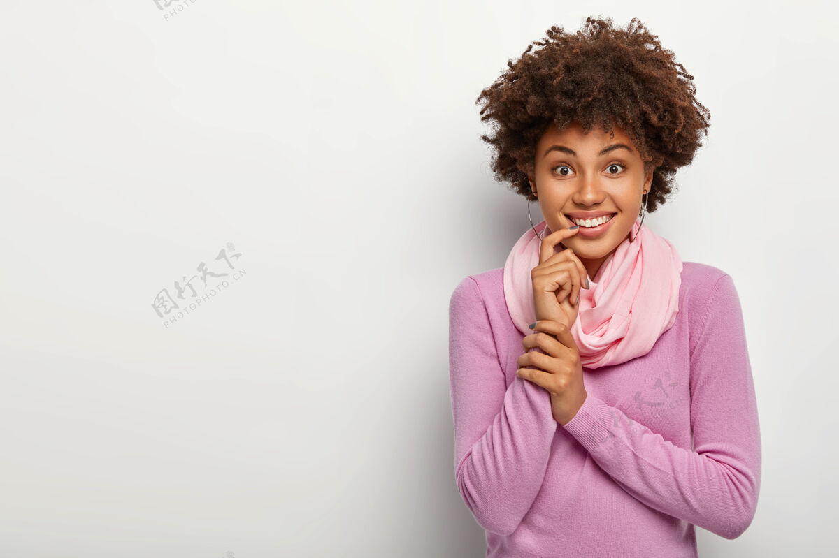 新鲜快乐的非洲裔女人 卷发 把食指放在嘴唇上 露出牙齿般的微笑 穿着随意脸皮肤人