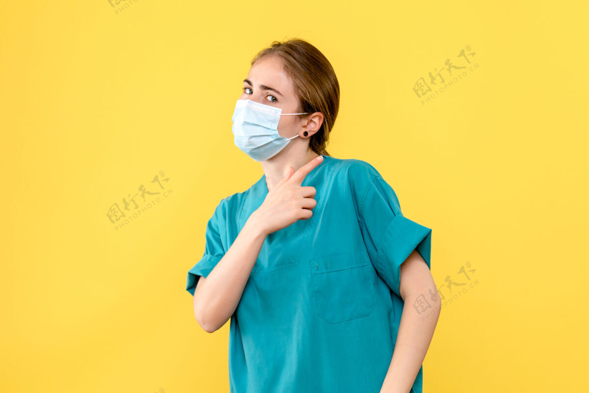 肖像正面图黄色背景上戴面罩的女医生卫生院大流行病毒女士脸微笑