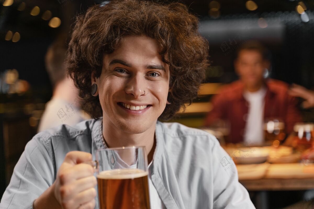 乐趣特写微笑的人拿着啤酒杯在酒吧特写酒吧享受