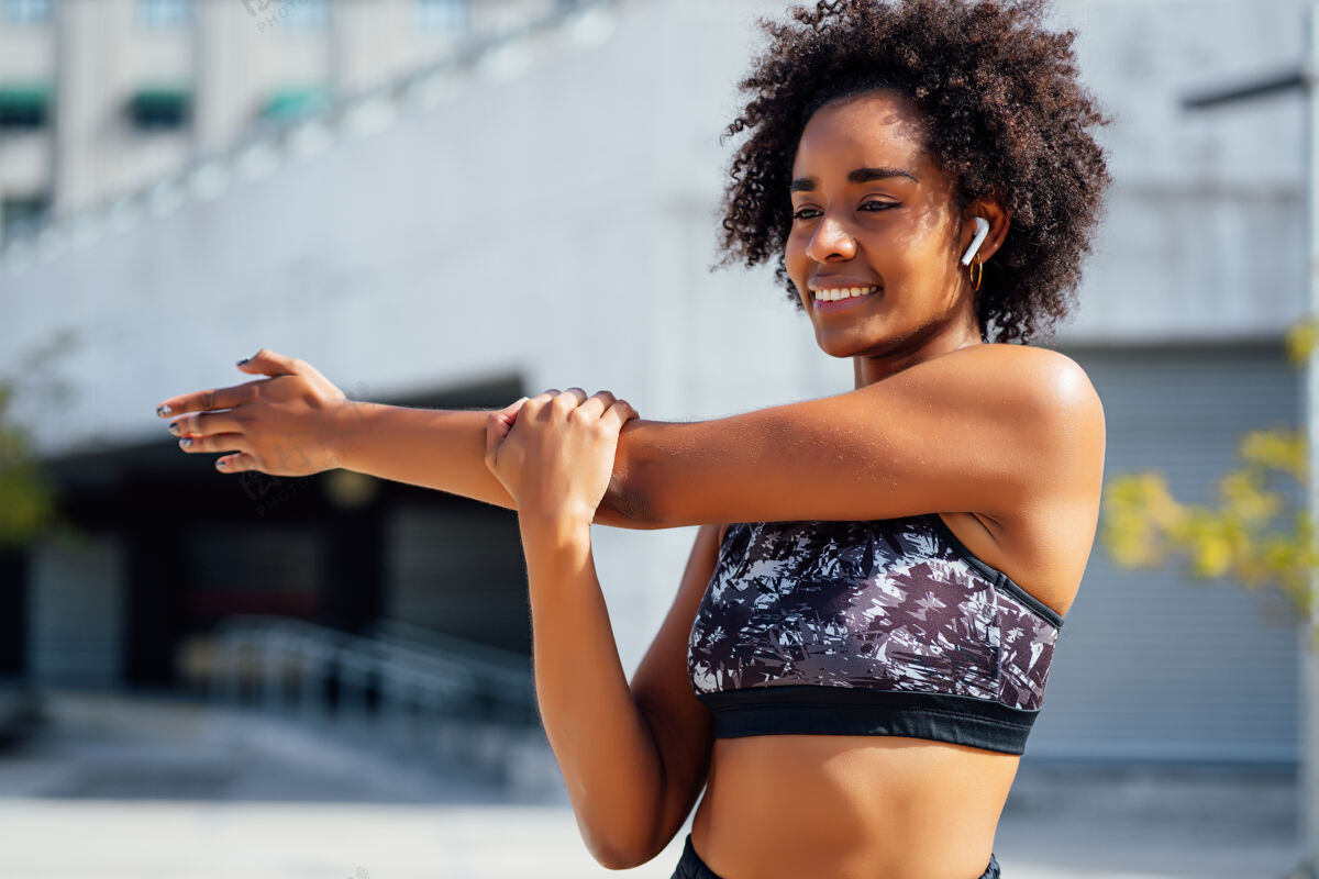 运动一位非洲运动女性在户外运动前伸展双臂热身成人运动健康