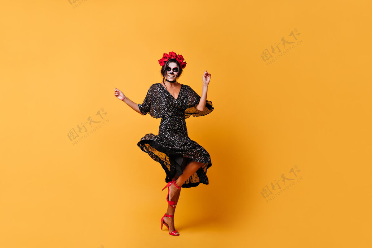 花身材苗条 皮肤黝黑 头戴花冠的墨西哥女人在橙色的墙壁上跳跃跳舞狂欢节女巫墨西哥