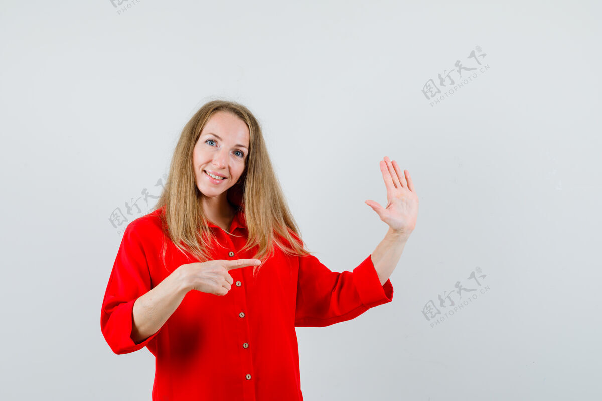 表演穿红衬衫的女士指着一边 露出手掌 看上去很高兴 病毒发型高级