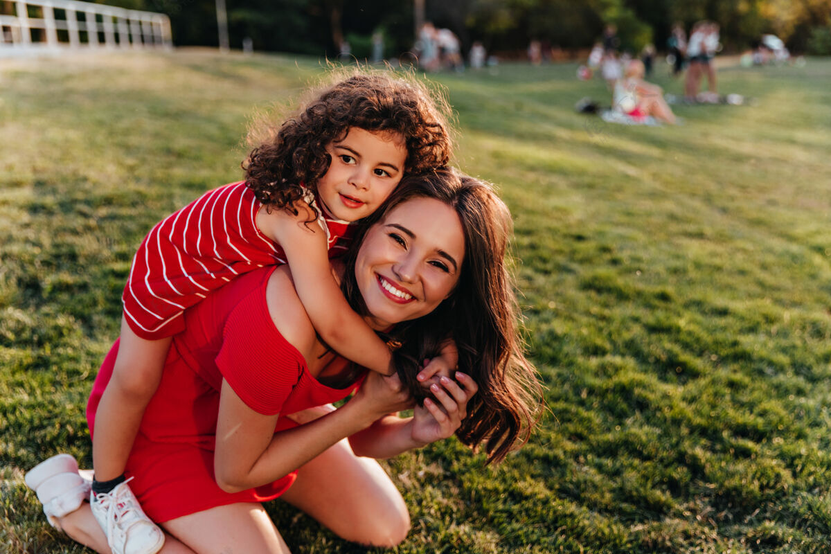 拥抱优雅的小女孩抱着妹妹在公园里和卷发的孩子玩着快乐的棕色头发的自然女模特游戏积极女儿