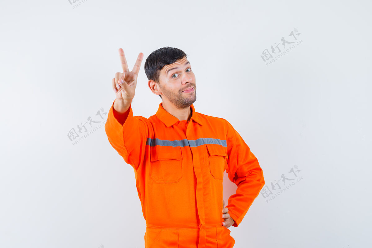 展示一个穿着制服的工业工人 脸上挂着v字 看上去很高兴 正对着前方劳工工程师监控