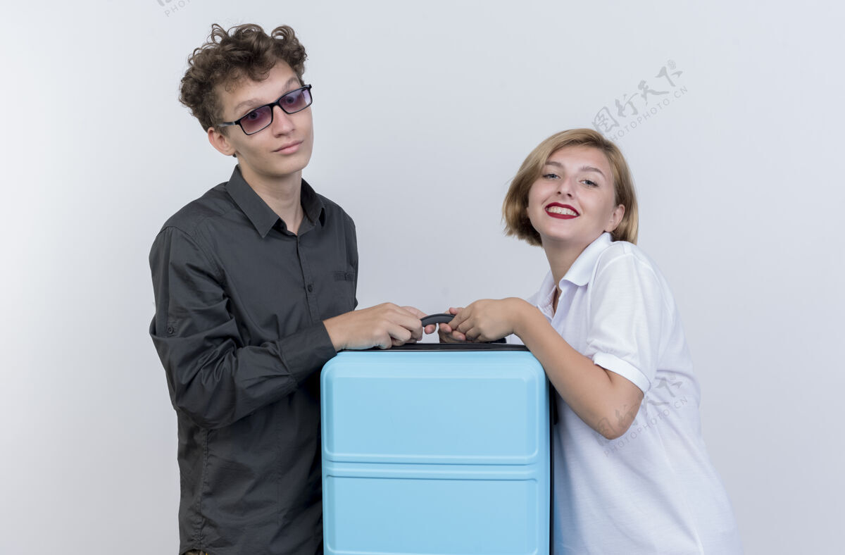 男人快乐的年轻一对旅游者男人和女人拿着手提箱微笑着越过白墙手提箱微笑年轻人