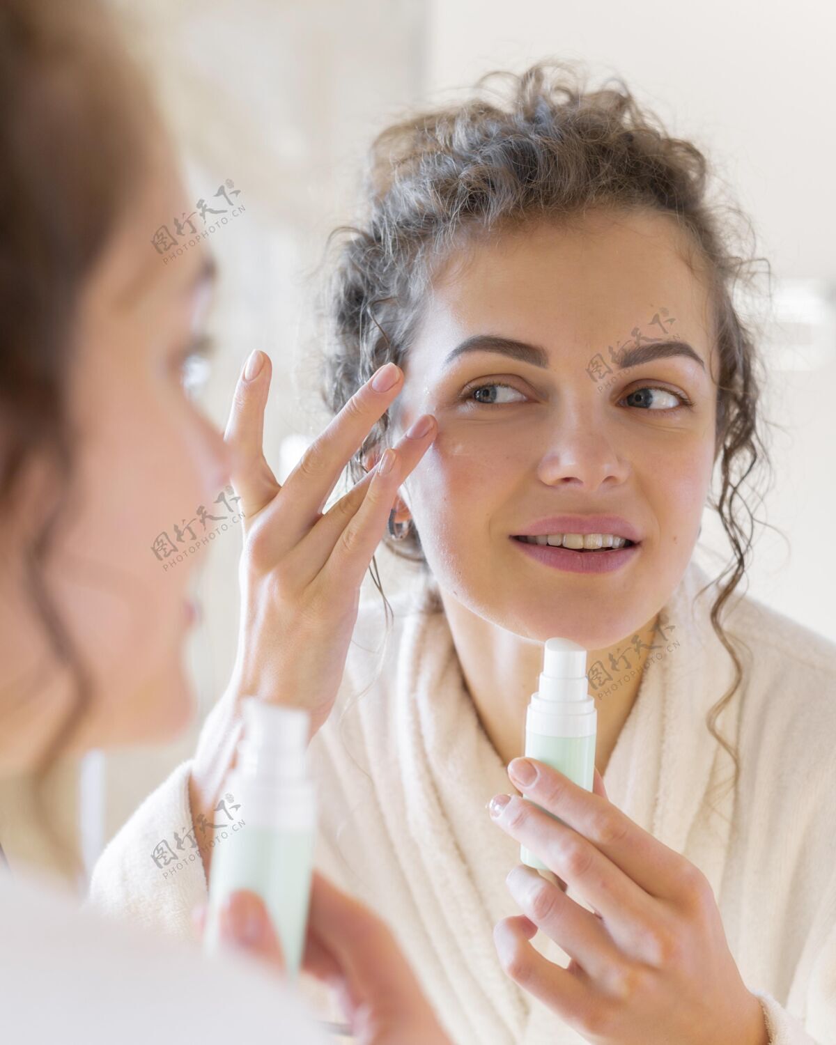 浴袍照镜子的时候在脸上涂面霜的女人室内女人房子