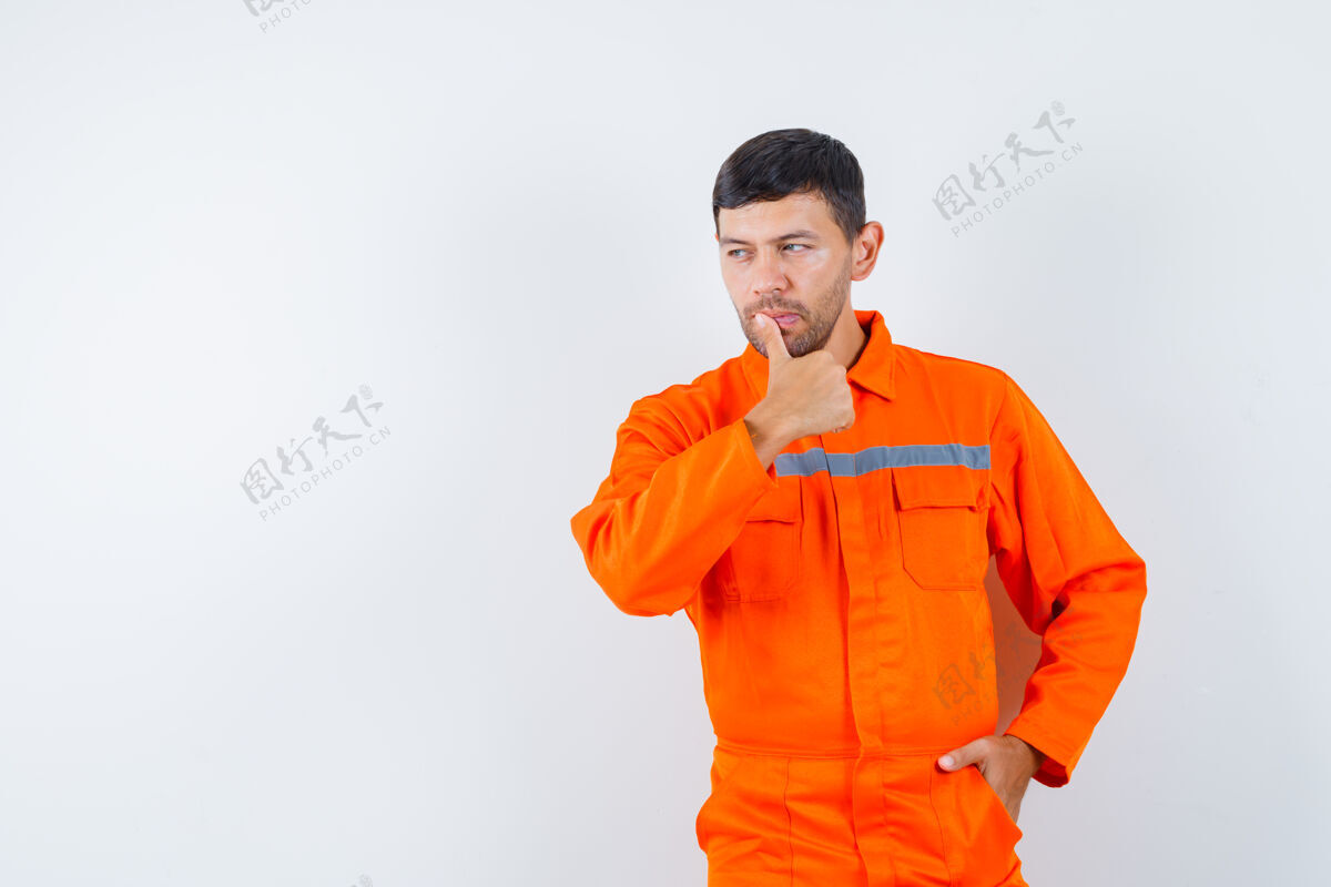 工作场所穿着制服的工业工人用手指捂着嘴唇看着别处 神情沉思前视图制服自动化监控