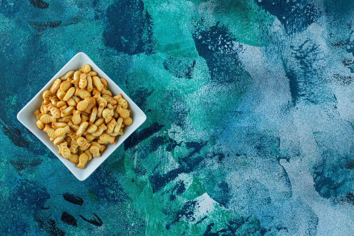 好吃的在蓝色的碗里放一个脆脆的饼干鱼顶视图鱼开胃菜