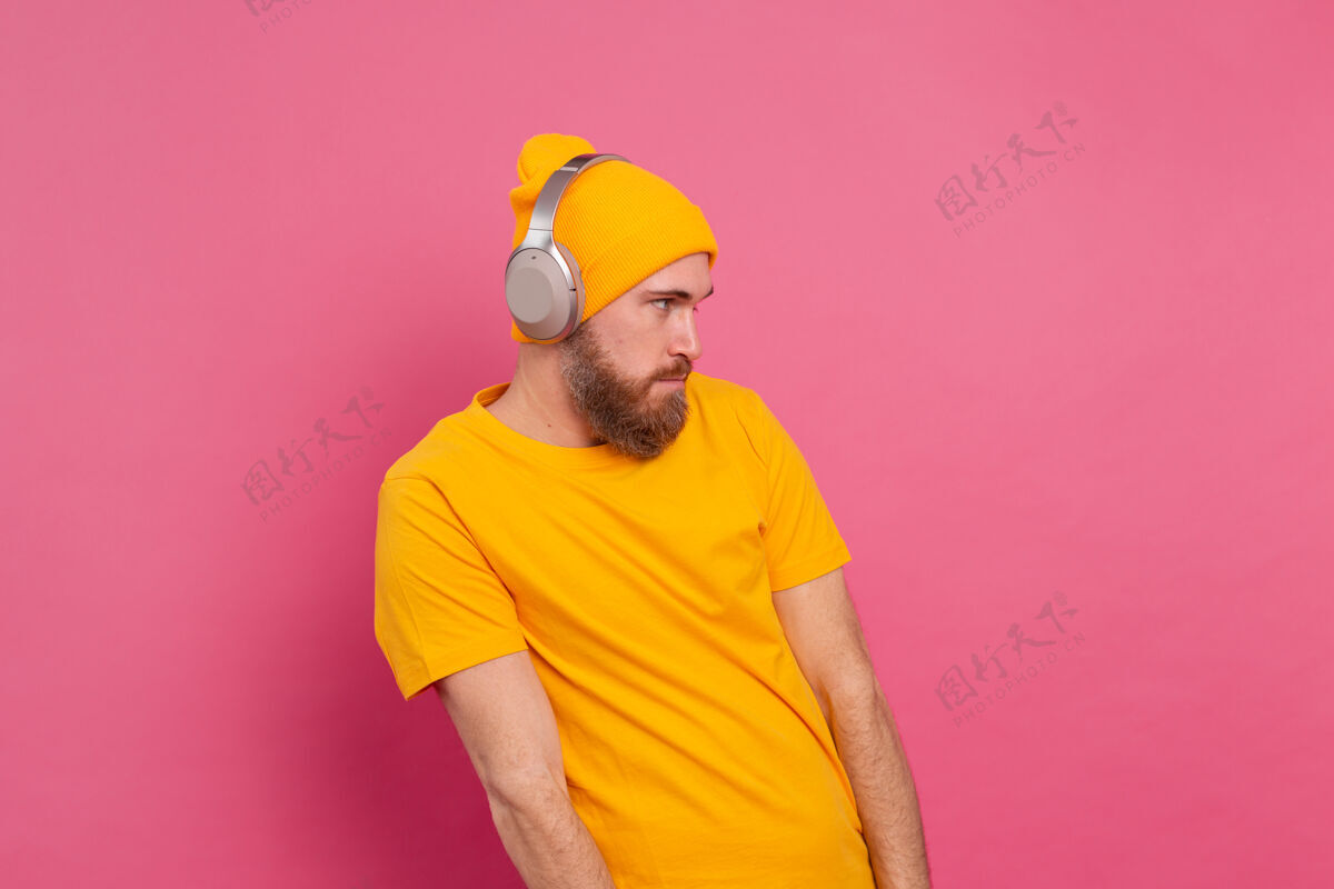 歌曲帅哥在随意地听着音乐 用耳机隔离在粉色背景上人物年轻背景