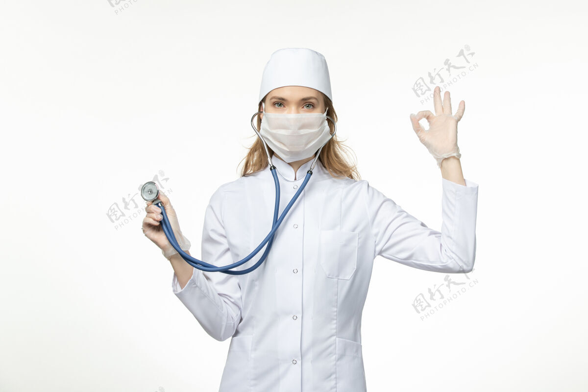 比赛前视女医生身穿医疗服戴口罩因冠状病毒手持听诊器白桌病毒大流行-冠状病毒病正面球员高尔夫球手