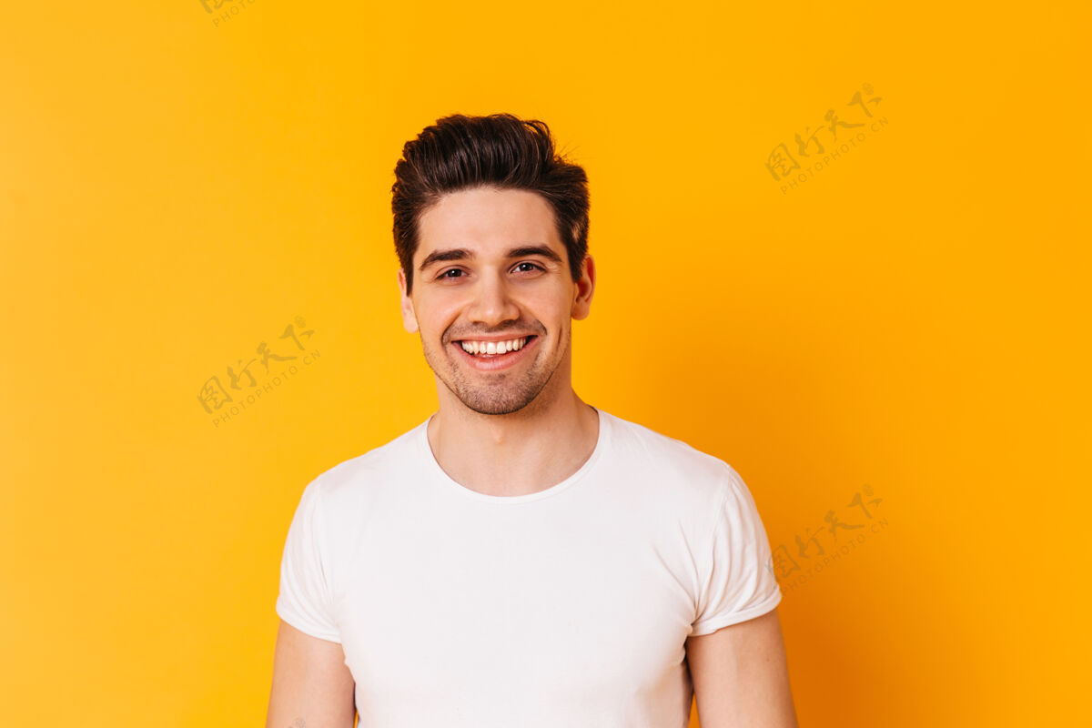 强壮身穿白色t恤的棕色眼睛男人的特写肖像男人在橙色空间微笑棕色眼睛姿势健康
