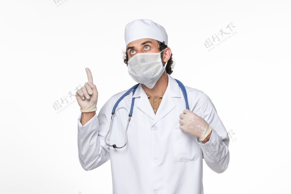 病毒正面图：男医生穿着医疗服 戴着口罩以防感染冠状病毒——并思考白墙病毒喷溅冠状病毒大流行防护医疗正面