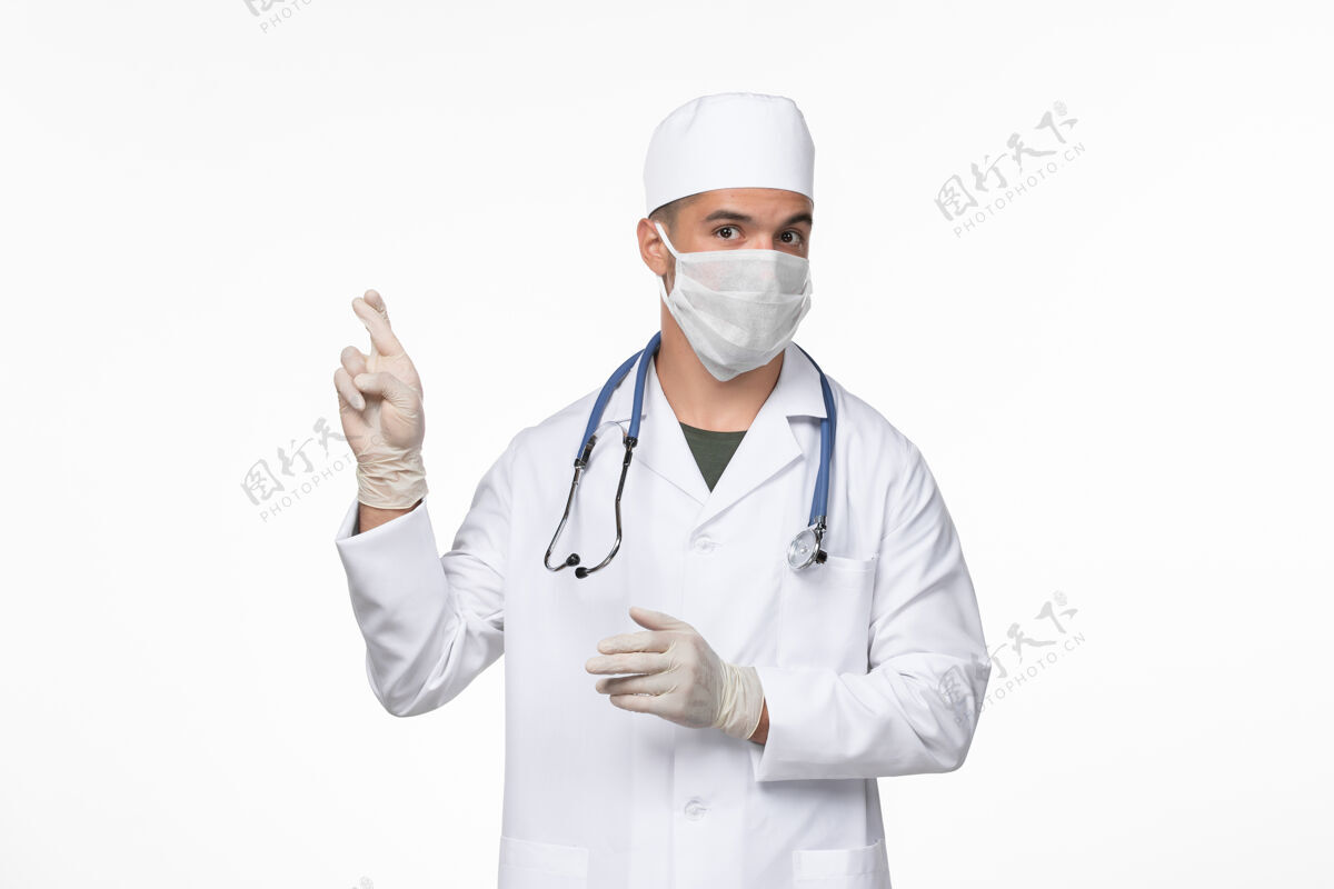 医生正面图：男医生穿着医疗服 戴着防冠状病毒口罩 上了淡白色的墙壁病毒冠状病毒-疾病大流行冠状病毒男性防护