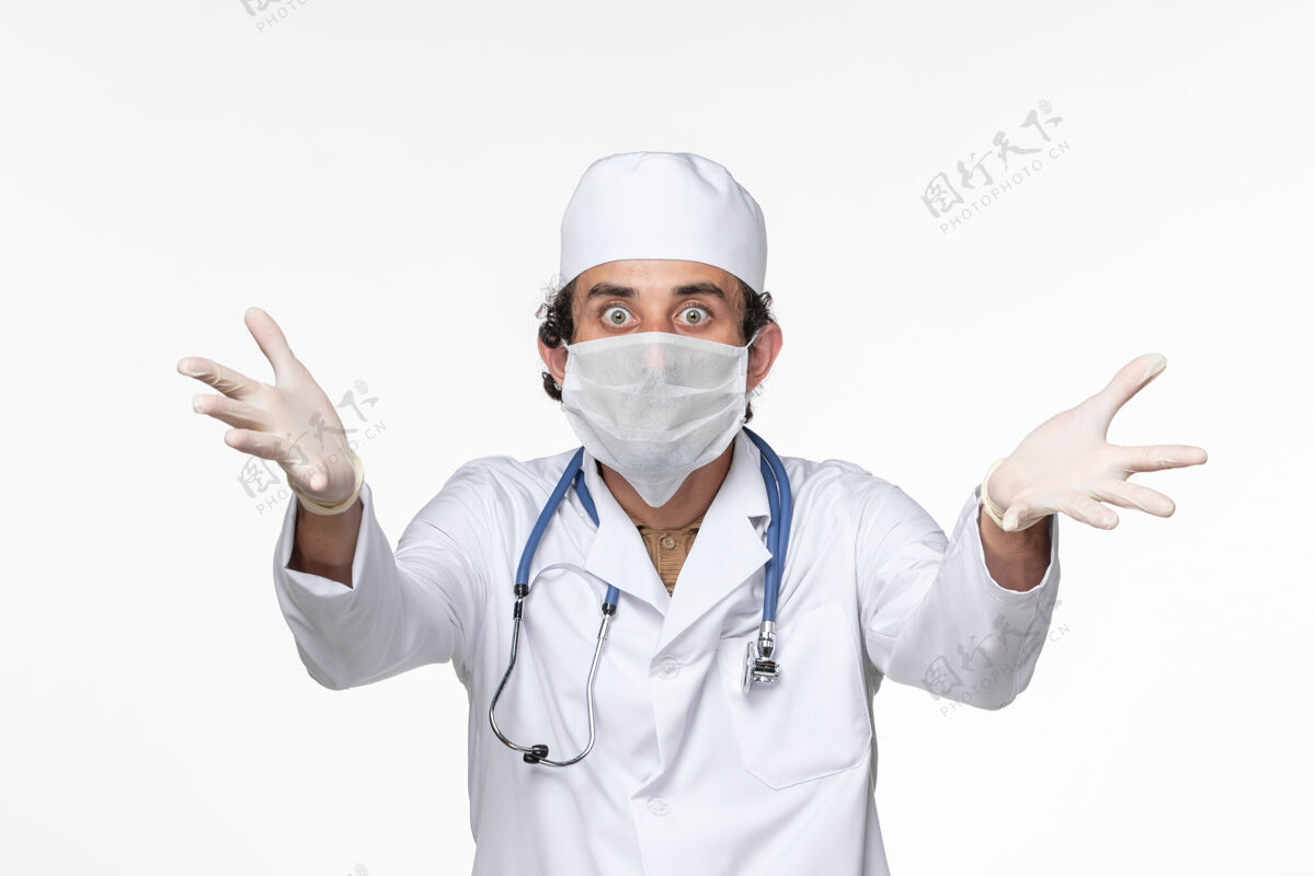 正面正面图男医生穿着医疗服 戴着无菌口罩 以防白色办公桌上的冠状病毒溅起冠状病毒大流行健康桌子防护医生