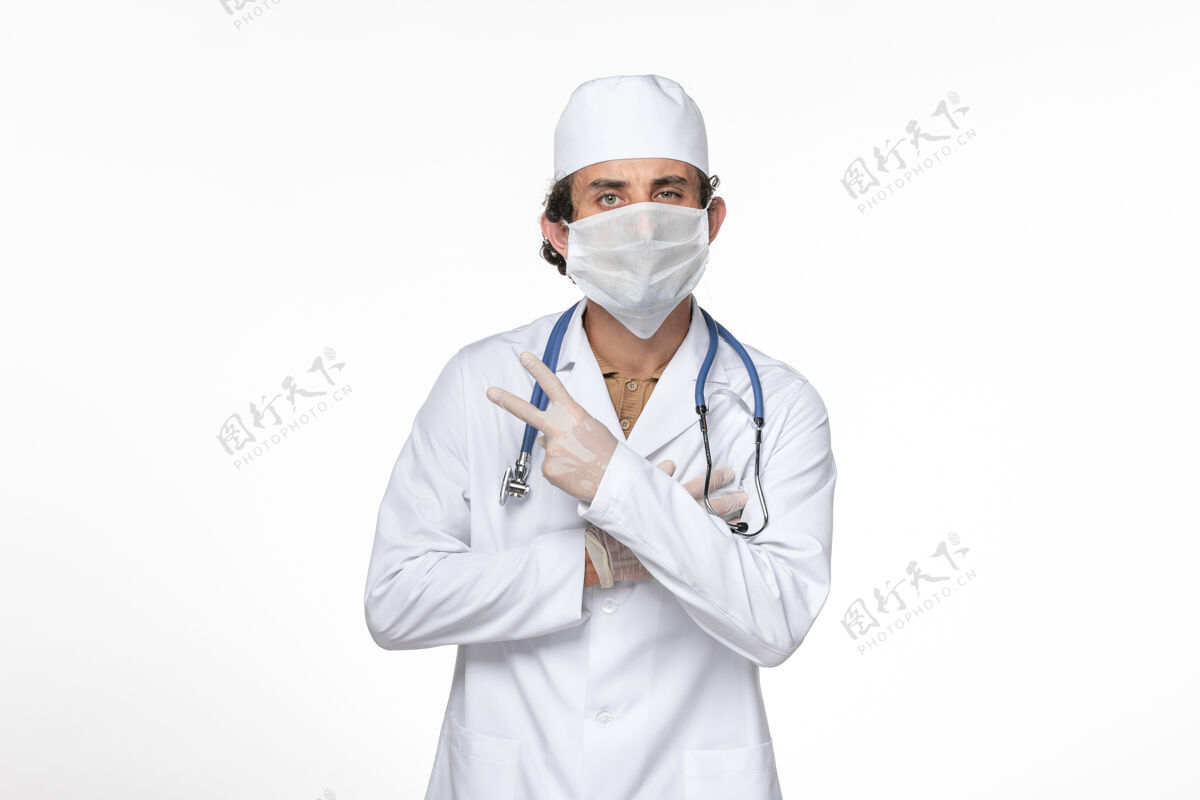 冠状病毒防护正面图男医生身穿医疗服 戴着防冠状病毒口罩上了淡白色的墙壁冠状病毒大流行药医疗视图专业