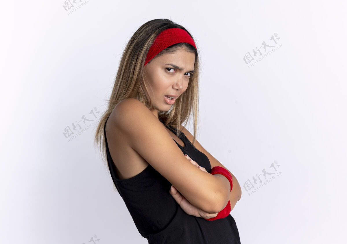女孩愤愤不平的年轻健身女孩 穿着黑色运动服 头戴红色头巾 站在白墙上站头带健康