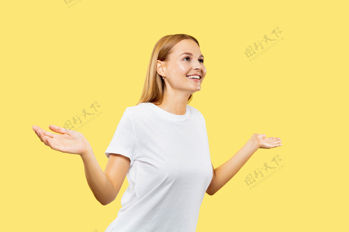 衬衫黄色工作室背景上的白人年轻女子半身像穿着白衬衫的漂亮女模特金发面部专业