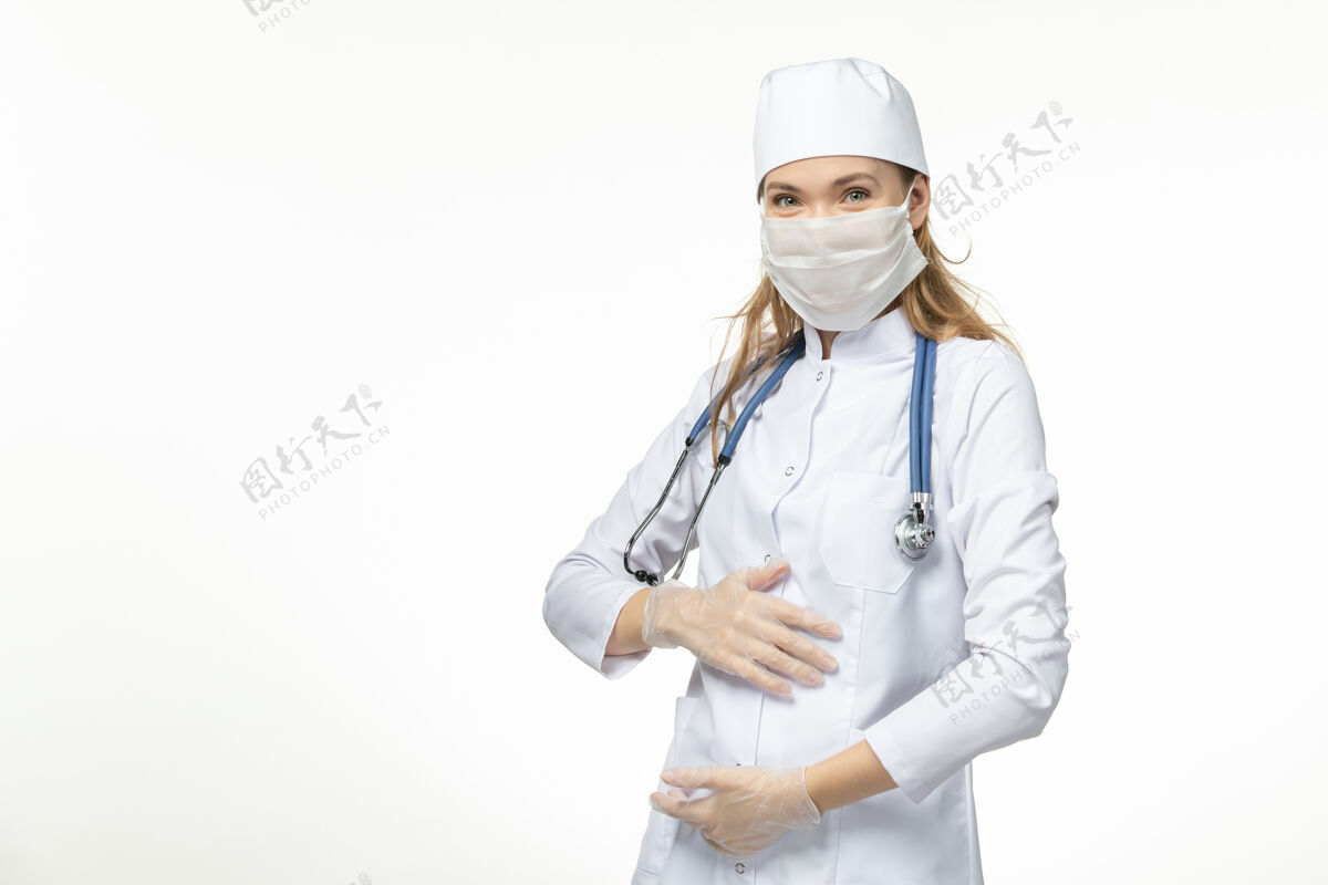 胃正面图女医生穿着医疗服 带着无菌口罩 因冠状病毒接触她的胃 白墙疾病大流行健康病毒冠状病毒预防冠状病毒防护医生