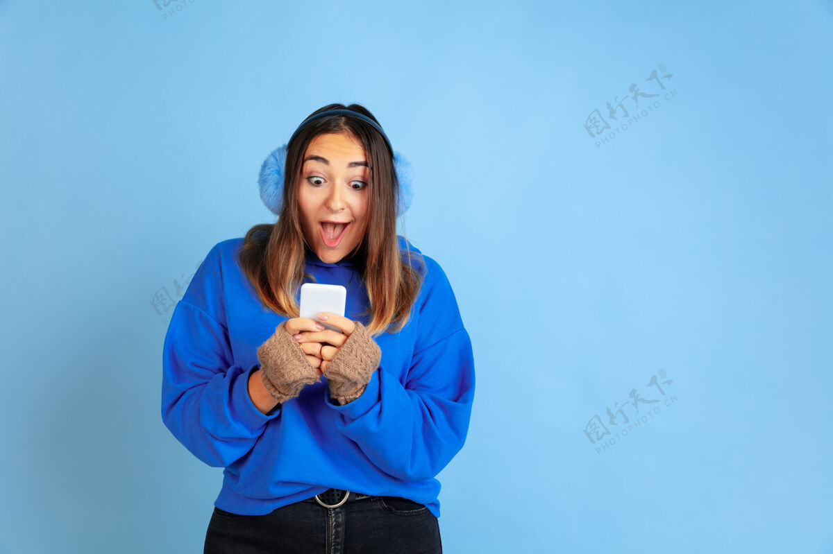 金融用手机 快乐蓝色空间上的白种女人肖像穿着暖和衣服的漂亮女模特一半女性职业