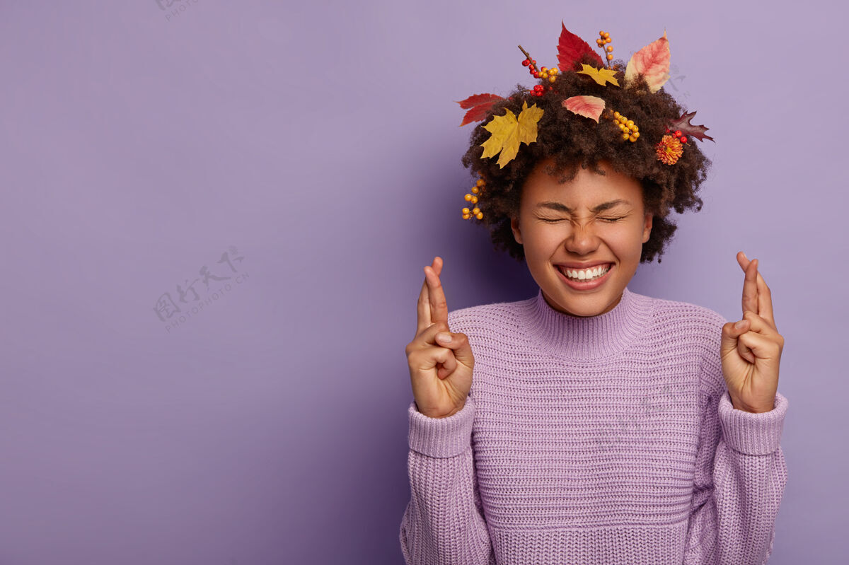 愿望梦幻般充满希望的非洲裔美国女孩相信胜利 在秋天祈祷 穿着针织套头衫 卷发里的叶子被隔离在紫罗兰色的墙上紫色肢体语言年轻