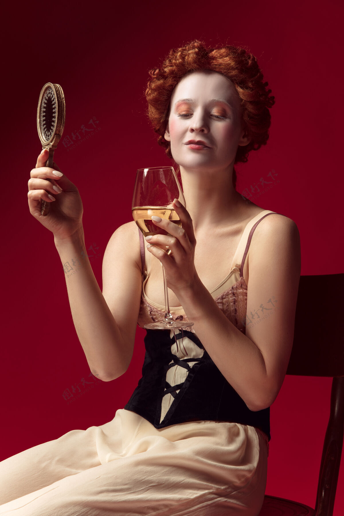 优雅中世纪的红发女公爵 身穿黑色紧身衣和睡衣 坐在红色空间里 一面镜子和一杯葡萄酒历史骄傲历史