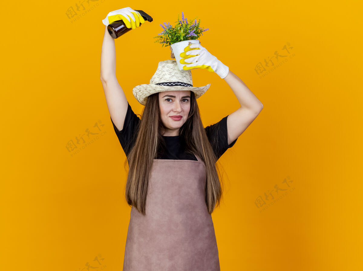 桔子高兴的美丽的园丁女孩穿着制服和园艺帽帽子漂亮花盆