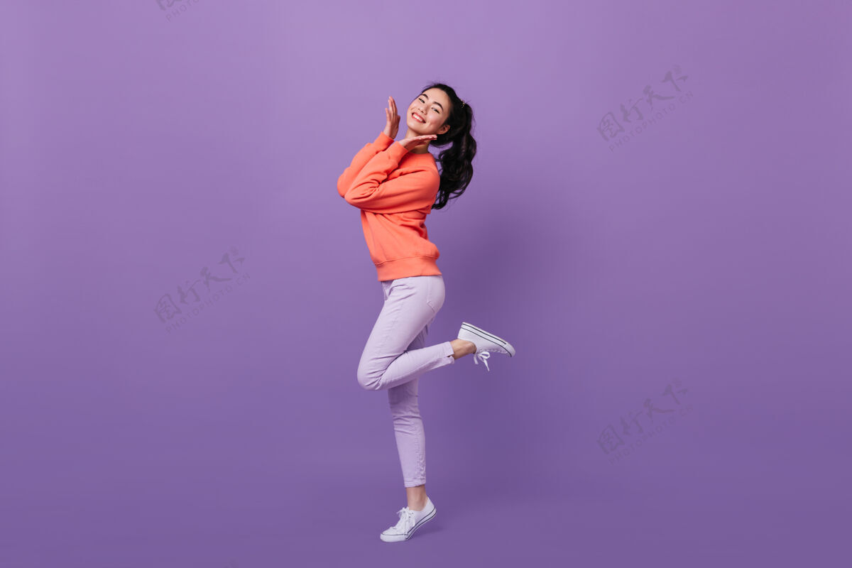 成功优雅的亚洲女人单腿站立极乐的中国女人在紫色背景下跳舞的全貌年轻亚洲服装