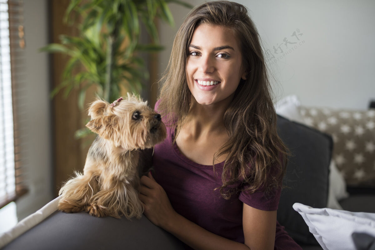 动物快乐美丽的年轻女子与她的小狗合影沙发姿势坐着
