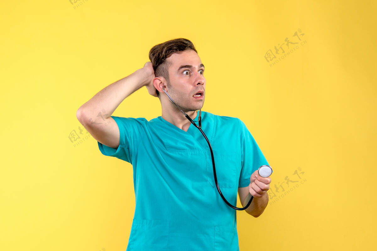 快乐黄色墙上年轻男医生使用听诊器的正面图男人年轻男医生医院